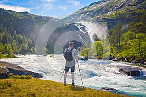 Men with a backpack watching the waterfall, Norway