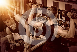 Men with barbell at gym. Color tone background.