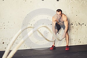 Men with battle rope battle ropes exercise in fitness gym