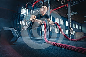 Men with battle rope battle ropes exercise in the fitness gym.