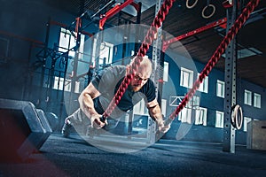 Men with battle rope battle ropes exercise in the fitness gym.