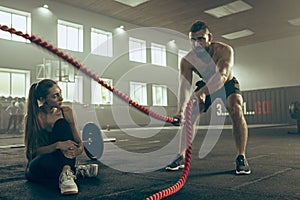 Men with battle rope battle ropes exercise in the fitness gym.