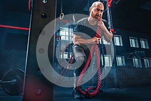 Men with battle rope battle ropes exercise in the fitness gym. CrossFit.