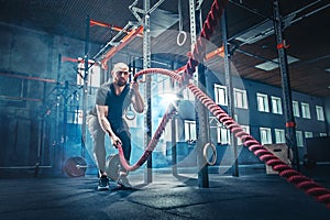 Men with battle rope battle ropes exercise in the fitness gym.