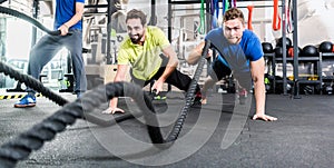 Men with battle rope in functional training fitness gym