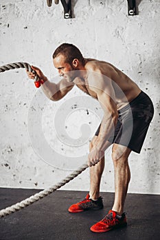 Men with battle rope battle ropes exercise in fitness gym