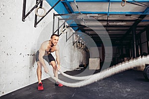 Men with battle rope battle ropes exercise in fitness gym