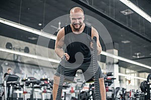 Men with battle rope battle ropes exercise in the fitness gym. CrossFit