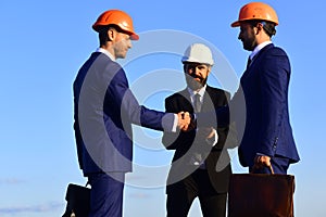 Men with beard and busy faces make deal shaking hands.