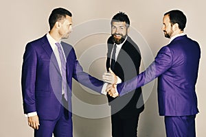 Men with beard and smiling faces discuss business or gage. Career and competition concept. Businessmen wear smart suits