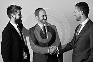 Men with beard and smiling faces make successful deal. CEOs shake hands on light grey background. Business and