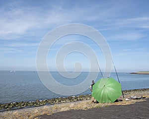 Men behind large green umbrella seek protection from the sun white fishing in waddenzee near harlingen in the netherlands