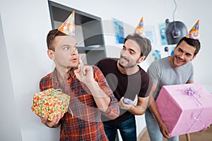 Men in birthday hats are preparing a surprise birthday party. They are preparing to meet the birthday girl.