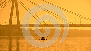 Men in boats sailing under bridge in big city during magic sunset, tourism