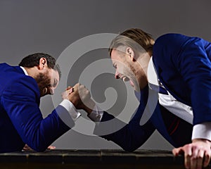 Men or businessmen with tense faces compete in armwrestling