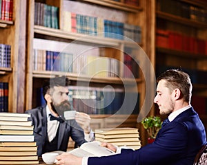 Men with busy faces reading books, studying and drink tea.