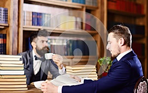 Men with busy faces reading books, studying and drink tea.