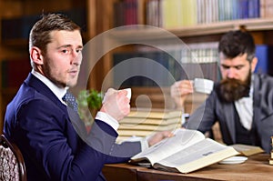 Men with busy faces reading books, studying and drink tea.