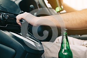 Men are in the car`s gear and ready to leave while having a beer bottle placed in the car
