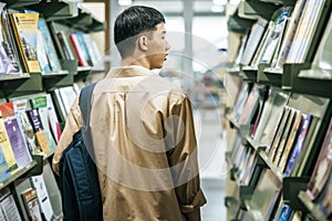 Men carrying a backpack and searching for books in the library