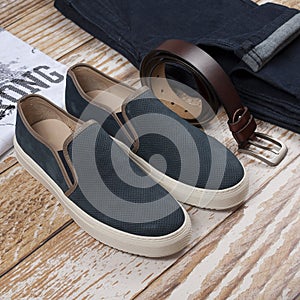 Men casual outfit. Men`s shoes, clothing and accessories on wooden background - jeans, shirt, sneakers, belt. Top view. Flat lay