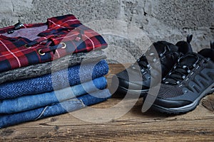 Men casual outfit. Men& x27;s shoes, clothing and accessories on wooden background - sweater, jeans, sneakers. Top view. Flat lay