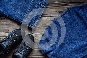 Men casual outfit. Men's shoes, clothing and accessories on wooden background - sweater, jeans, sneakers. Top view. Flat lay
