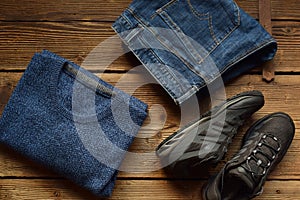 Men casual outfit. Men& x27;s shoes, clothing and accessories on wooden background - sweater, jeans, sneakers. Top view. Flat lay