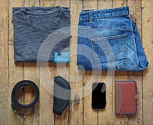 Men casual outfits. Men shoes, clothing and accessories on wooden background - grey t-shirt, blue jeans, sneakers with eyeglass