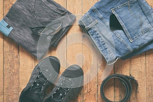 Men casual outfits. Men shoes, clothing and accessories on wooden background - grey t-shirt, blue jeans, sneakers with eyeglass