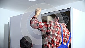 Men in checkered shirt holds side of the wardrobe