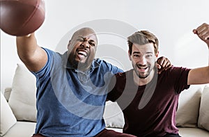 Men cheering sport together at home