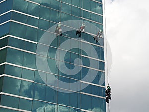 men cleaning glass building by rope access at height