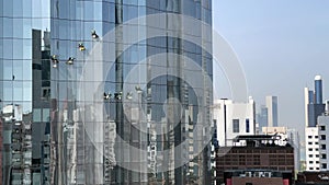 Men cleaning the glass windows of a luxury tower - View of modern offices and skyscrapers - Abu Dhabi city