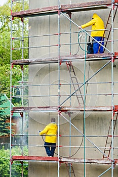 Men cleaning wall. Scaffolding