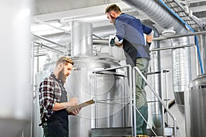 Men with clipboard at brewery kettle or beer plant