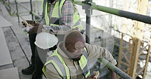 Men, construction workers and eating on lunch break, safety wear and employee on scaffolding. Professional, building
