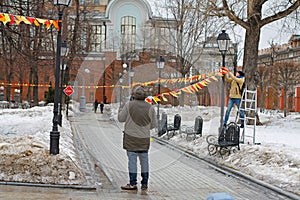 Men decorate with colorful flags in the Park Hermitage for the holiday in Moscow