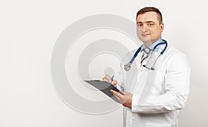 Men doctor writes with a pen a document on a tablet, writes a medical history