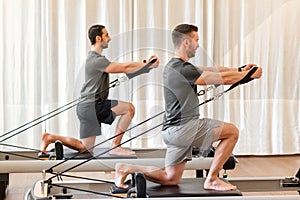 Men doing pilates exercise on reformer bed