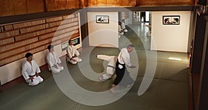 Men in dojo with sensei for aikido training, fitness and development with action, exercise and coaching. Teaching