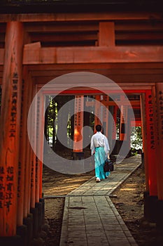 Men dress like Shinto priests, wearing white shirts and green pants. Rear view, walking on a walkway