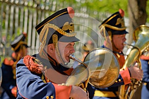 A men dressed in an old military uniform playing the trumpet
