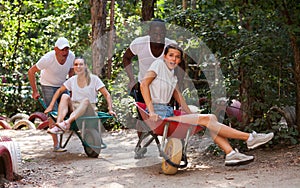 Men drive their girls in garden wheelbarrows. Funny amusement park amusement park