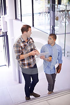 Men, employee and office with tablet on stairs for online research, ideas and creativity as graphic designers. Teamwork