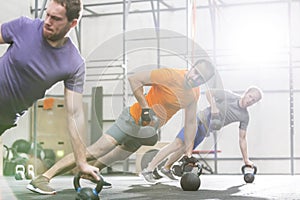 Men exercising with kettlebells in crossfit gym