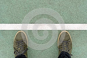 Men feet in green leather sneakers stand on the rubberized track,  on a start line