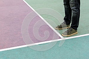 Men feet stand on the rubberized sports playground painted in pastel colors