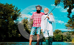 Men fishing. Fishing anglers in river water. Old and young fisherman.