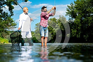 Men fishing in river during summer day. Still water trout fishing. Difference between fly fishing and regular fishing